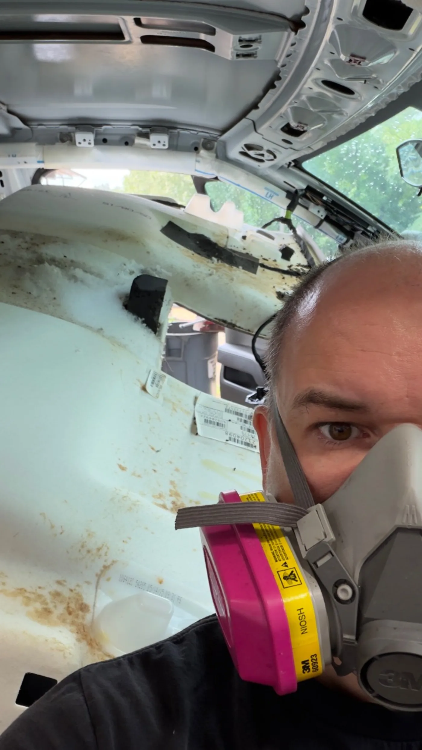 Quack & Wax technician wearing respiratory protection during a headliner inspection